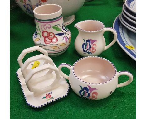 A collection of Poole pottery comprising vase, toast rack, twin-handled sugar bowl and milk jug with floral pattern