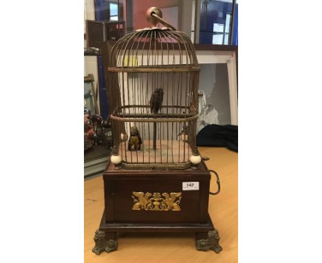 A 19th Century French Singing Bird automaton as two birds in a cage on a mahogany base with Empire style gryphon mount, raise