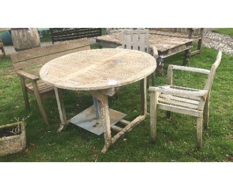 A teak garden table with two teak chairs and a bench