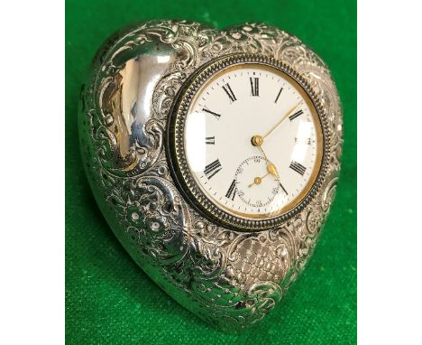 An Edwardian silver mounted dressing table clock of love heart form with embossed decoration, the white enamel dial set with 