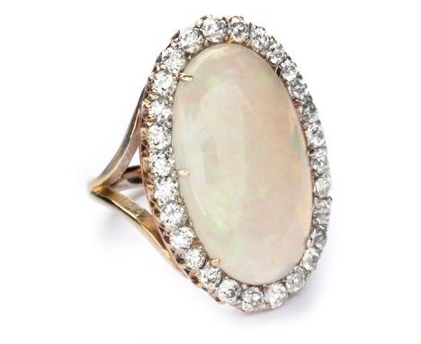  An Edwardian Opal And Diamond Cluster Ring centred with an oval opal, enclosed with a conforming surround of old European-cu