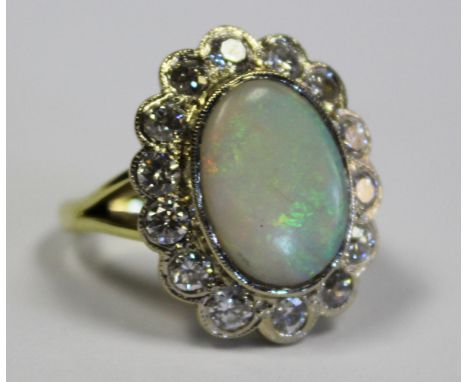  An Opal and Diamond Cluster Ring the central oval opal surrounded by a conforming band of milligrain-set round brilliant-cut