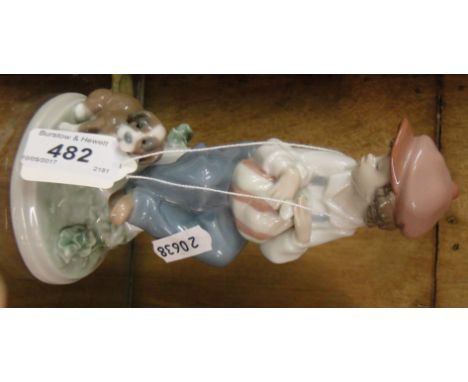 A Lladro figure of a boy sitting with a puppy.