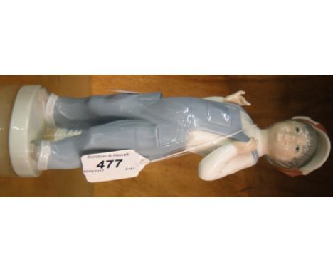 Lladro boy in dungarees wearing a red and white cap.