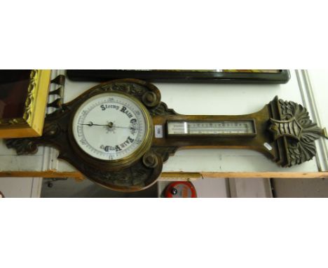 A barometer with thermometer in carved oak frame.
