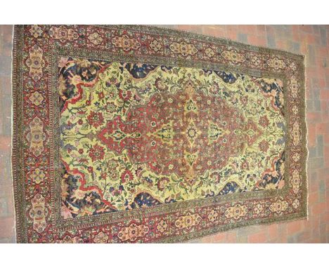 A Middle Eastern, probably Persian, beige ground rug with central scroll foliate medallion, floral spandrels, multiple border
