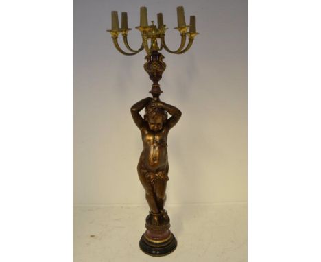 A late 19th Century, probably French, bronzed and marbled cast iron figural floor standing lamp, modelled as a cherub holding