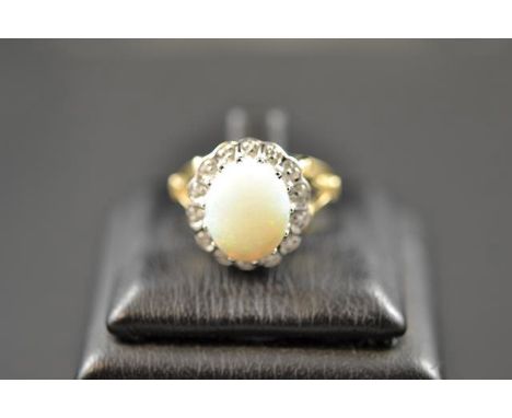 A 9ct gold ring with central opal surrounded by diamonds in cluster setting, size P1/2. CONDITION REPORT: Good condition.