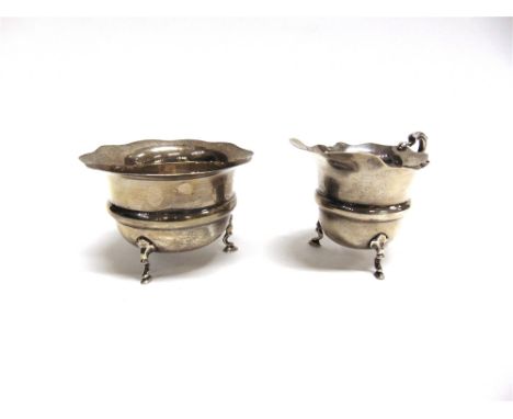 A SILVER CREAM JUG AND SUGAR BASIN by S Blanckensee & Sons Ltd, Birmingham 1927, of O round, cut rim form, on three supports,