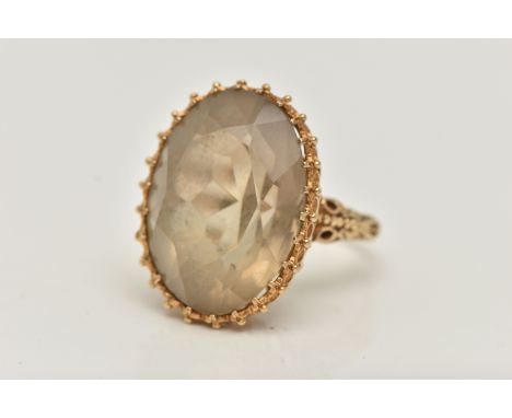A 9CT GOLD SMOKY QUARTZ DRESS RING, designed as a large oval cut smoky quartz, claw set with applied bead work surround, quar