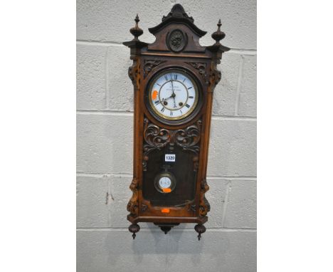 A LATE 19TH / EARLY 20TH CENTURY WALNUT WALL CLOCK, with an arched crest, flanked by twin finials, the single door enclosing 