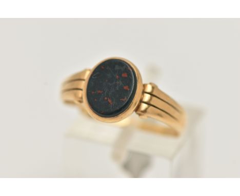 AN 18CT GOLD BLOODSTONE SIGNET RING, designed as a polished oval bloodstone inlay, collet set to the textured shoulders and p