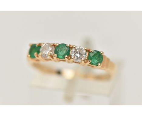 A YELLOW METAL EMERALD AND DIAMOND HALF ETERNTIY RING, set with two round brilliant cut diamonds, each in a four claw setting