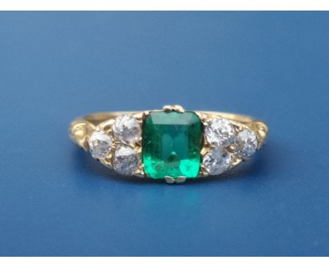 An emerald &amp; diamond ring, the rectangular cut emerald flanked by six small old cut diamonds on yellow metal shank.  Fing