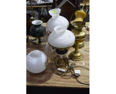 A Victorian brass students lampOf typical form with a cylindrical reservoir opposed by an opaque glass shade, along with a mo