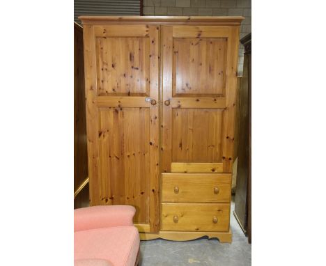 A modern pine compactum wardrobeHaving a moulded cornice above full length door apposed by a smaller cupboard door over two d