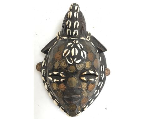 An African tribal mask from Tika Tribe in French Cameroon decorated with coins and cowry shells 