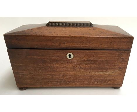 A mid 19th century mahogany sarcophagus shaped tea caddy, the hinged lid enclosing two covers and glass, on bun feet. 