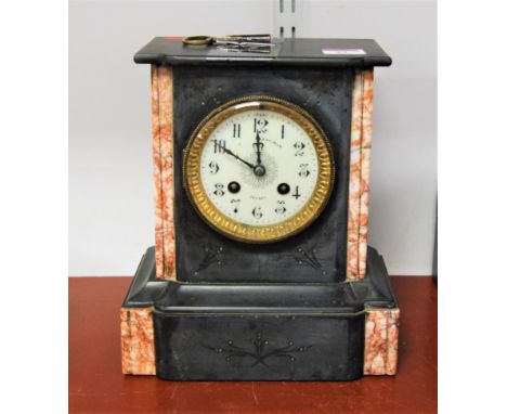 A late Victorian black slate and rouge marble cased mantel clock having an enamel dial with Arabic numerals and eight day mov