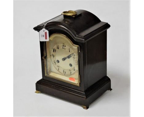 An early 20th century ebonised cased mantel clock, having an arched silvered dial with Arabic numerals, eight day movement st