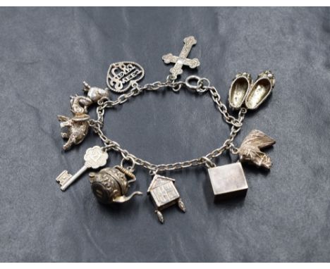 A silver belcher link charm bracelet, having ten silver and white metal charms, including a cross, a poodle, a ten pound note