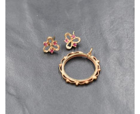 A pair of 9ct gold and ruby stud earrings, the pierced floral motif earrings set with three round cut rubies on post backs, a