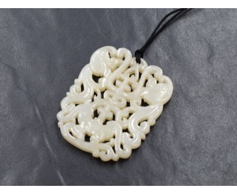 A carved jade pendant, of pierced form having a central character with decorative scroll work, on a black cord necklace, 5.5c