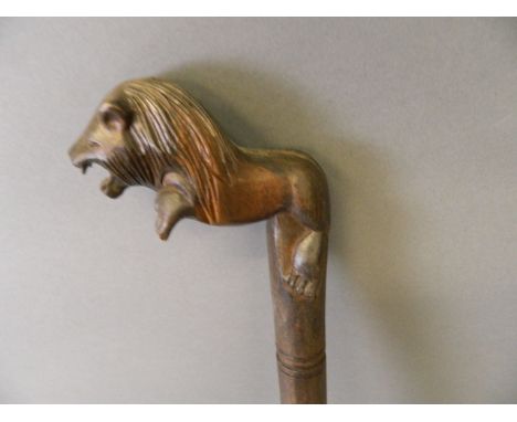 A carved hardwood walking stick, the handle in the form of a rampant lion, 36'' high 