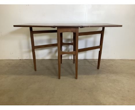 A mid century gate leg table. Teak veneered. W:135cm x D:76cm x H:73cm