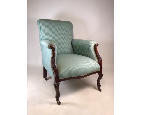 A late Victorian mahogany upholstered armchair with carved details to arms. Brass and ceramic castors. W:70cm x D:72cm x H:90