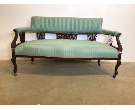 A late Victorian mahogany two seater sofa on brass and ceramic castors.W:139cm x D:60cm x H:77cm