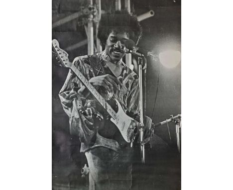 A large original 1960s black and white poster of Jimi Hendrix in concert, in classic pose with one of his trademark Fender St