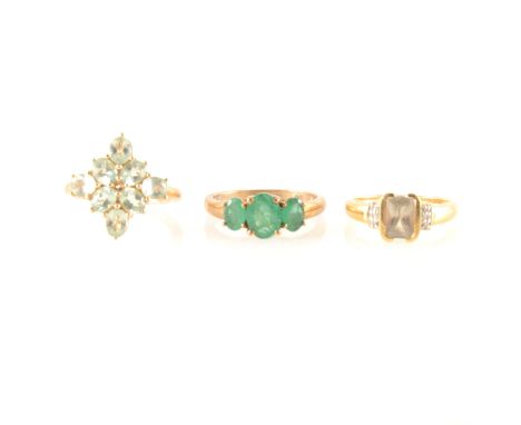 Three dress rings, an emerald three stone ring, amblygonite cluster ring, zultanite and diamond ring, the three emeralds claw