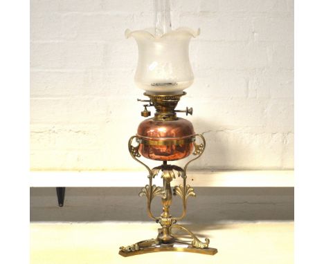A brass oil lamp, tri-form base, copper reservoir complete with shade and chimney, 69cm.