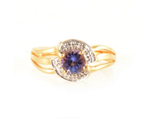 A circular tanzanite and diamond crossover ring, the tanzanite four claw set in an 18 carat yellow and white gold mount with 