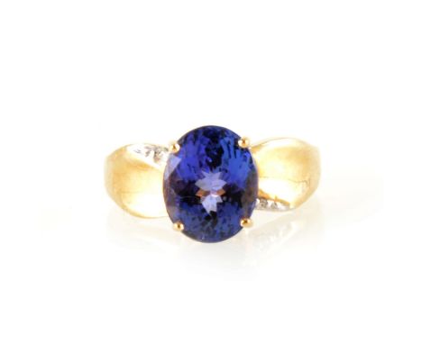 An oval tanzanite and diamond ring, the oval tanzanite 10mm x 8mm, four claw set in a 9 carat all yellow gold mount with wide