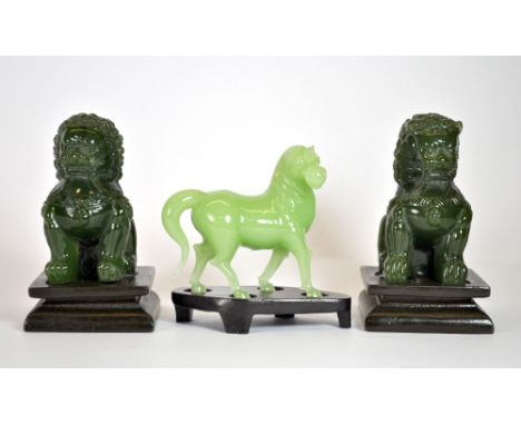 A pair of Chinese green glass lion figures with wooden stands imitating jade (H. 11cm), together with a jade style glass hors