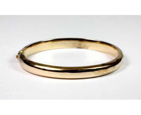 A yellow metal (tested min 9ct gold) hinged bangle, W. 6.5cm, approx 9.5g.