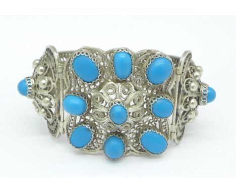 A white metal filigree bangle set with blue 'stones'