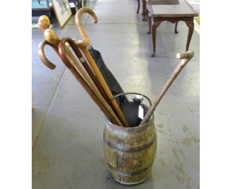 A PAINTED WOOD BARREL ADAPTED AS A STICK STAND CONTAINING SEVERAL WALKING STICKS, CANES AND UMBRELLAS