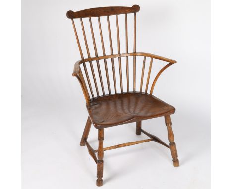 A George III elm comb back Windsor chair, having a turned spindle back raised on a shaped seat and turned legs and stretchers