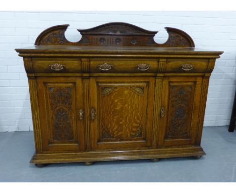 Oak ledgeback sideboard, the rectangular top over three frieze drawers above three carved panel cupboard doors, on plinth bas