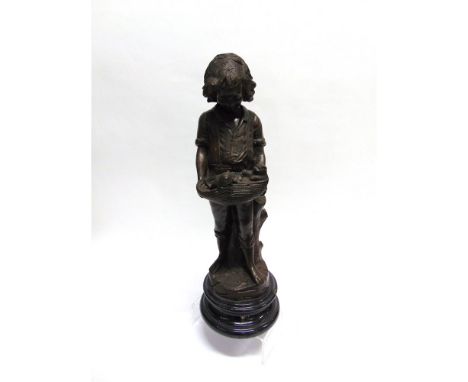 A BRONZED FIGURE MODELLED AS A YOUNG BOY  leaning against a tree trunk holding a basket with two kittens, on circular marble 