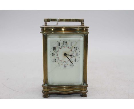 An early 20th century lacquered brass carriage clock of serpentine outline having enamelled dial with Arabic numerals, visibl