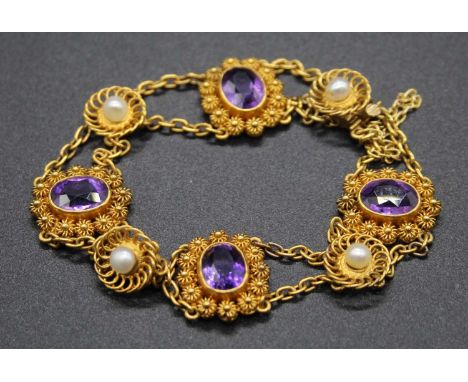 An early 20th century yellow metal, amethyst and seed pearl set sectional bracelet, arranged as alternating flowerheads on do