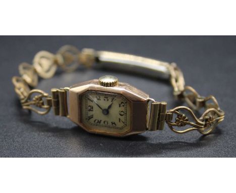 A lady's vintage 9ct gold cased Art Deco influenced tank watch, case dia. 15mm, on gilt metal bracelet 