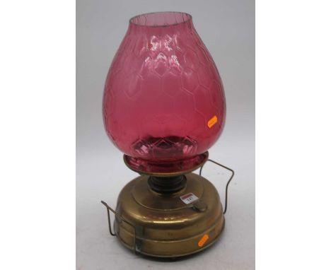 A Victorian brass oil lamp, the large cranberry tinted glass shade above a plain brass font, height 44cm