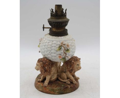 A Sitzendorf porcelain oil lamp, the basketweave font upon three lion supports, h.22cmThe shade holder is bent.The floral dec