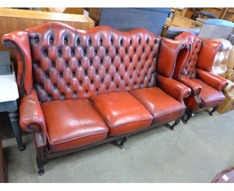 A Chesterfield red leather wingback sofa (tear to arm) and matching armchair