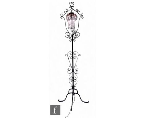 A wrought iron standard lamp with pink bubble glass shade suspended in a cartouche frame on scroll base, height 179cm. Condit